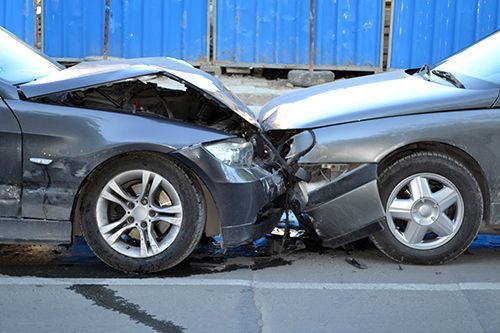 two cars are damaged in a car accident on the side of the road .