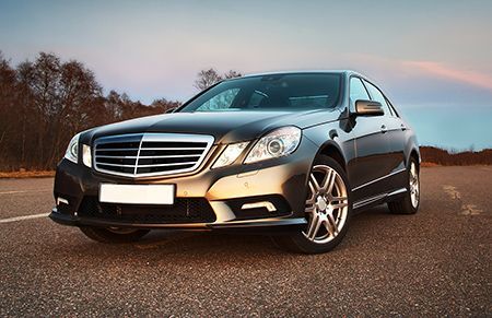A black mercedes benz is parked on the side of a road.