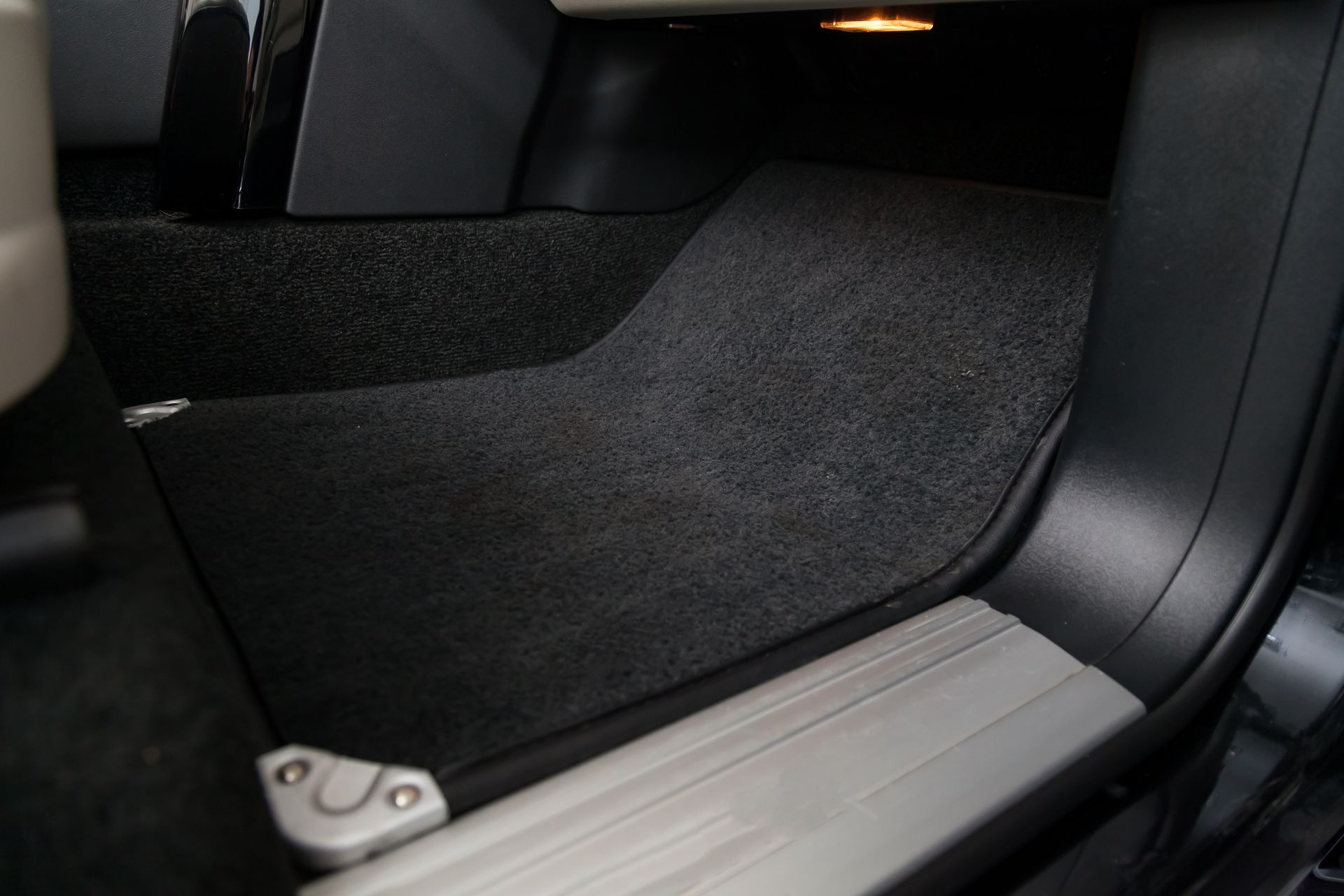 Un gros plan d'une portière de voiture avec un sol recouvert de moquette.
