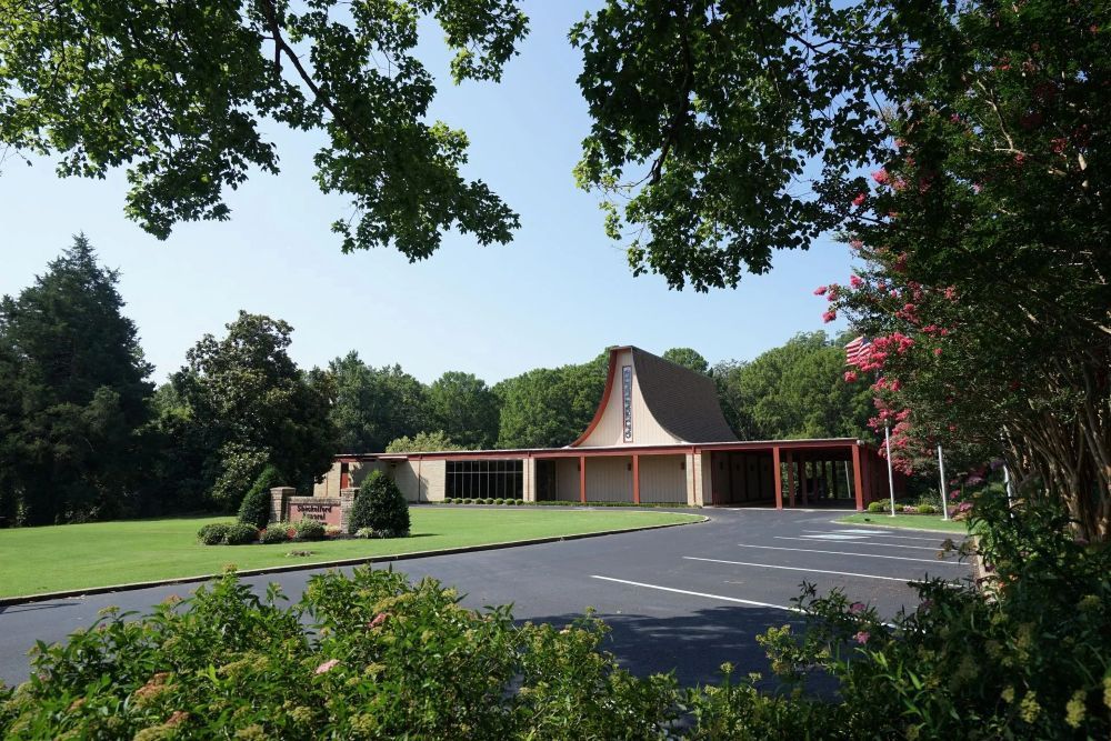 Cream-colored building with red tile roof, American flag, and green lawn.