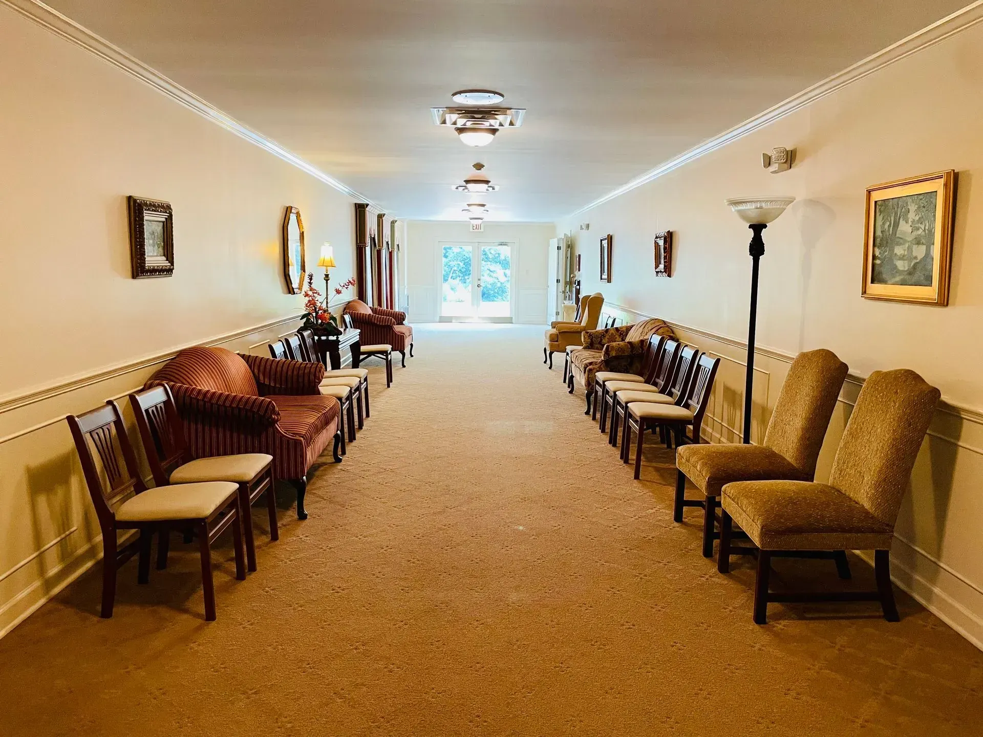 Long hallway waiting room with chairs along both walls and ceiling lights