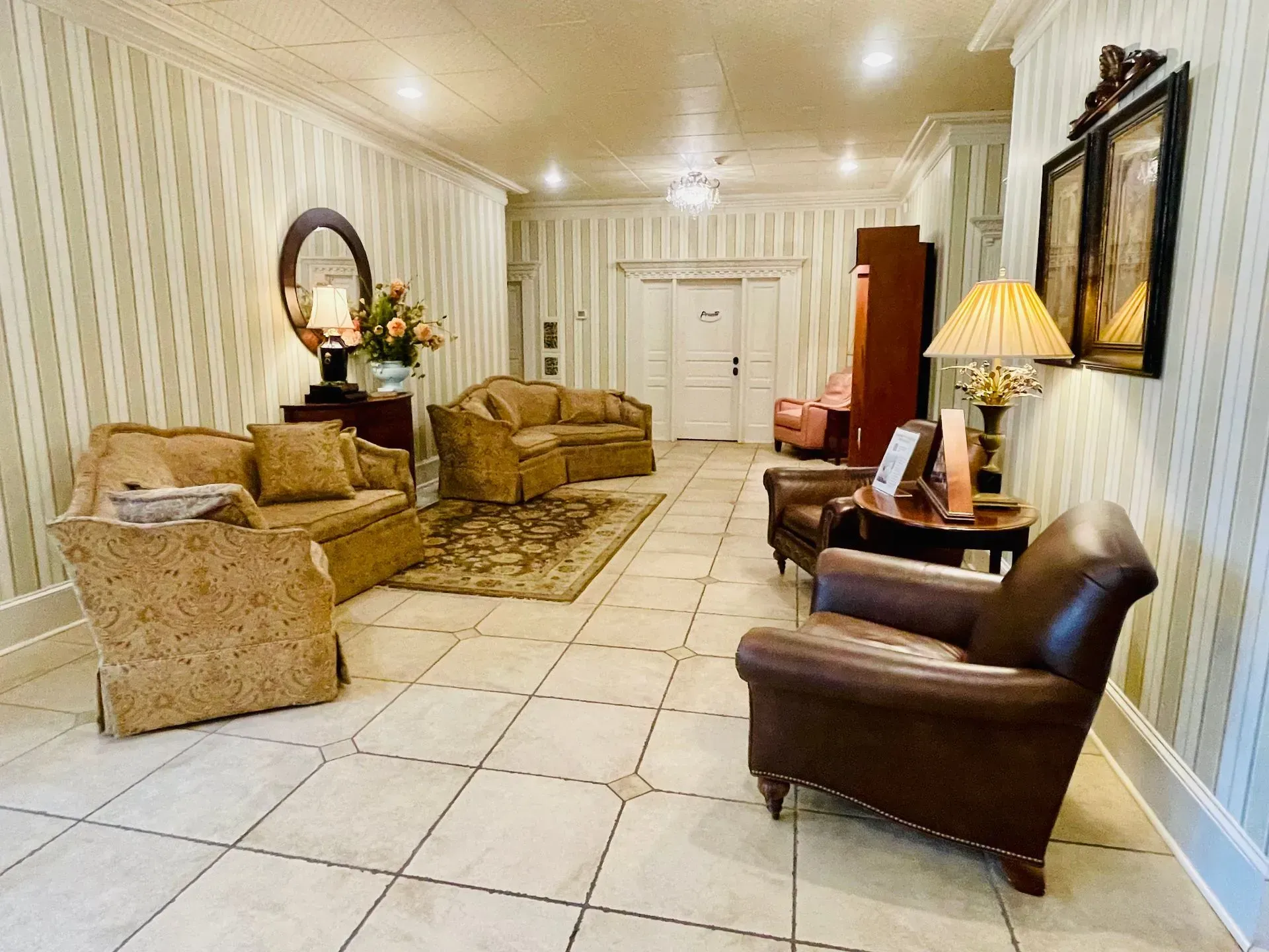Elegant beige living room with tiled floor, sofa, armchairs, and table lamps