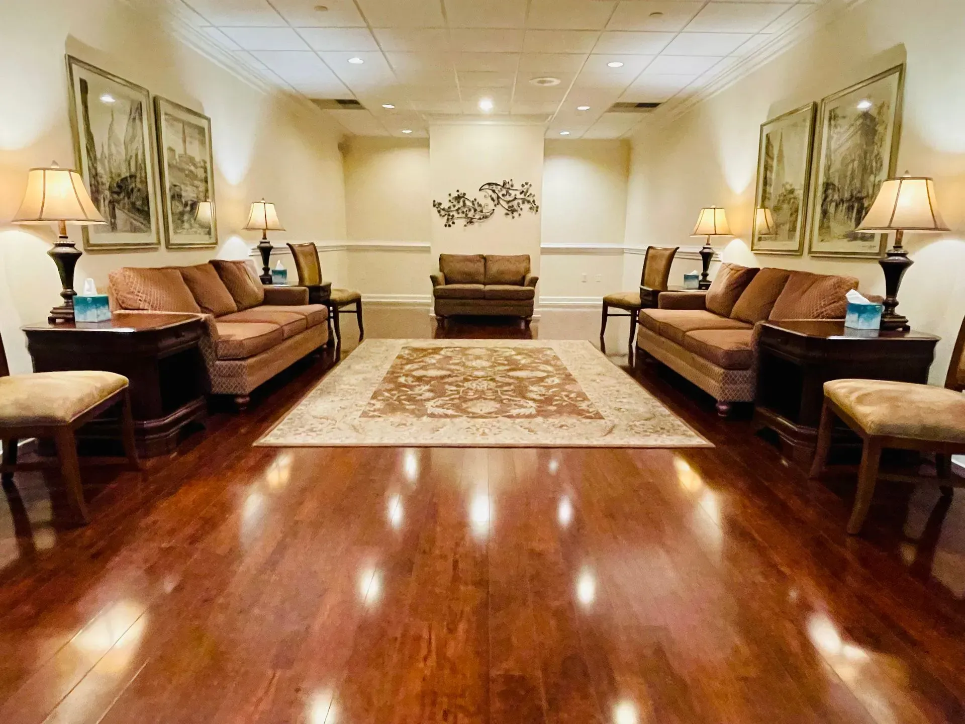 Elegant living room with polished hardwood floors, sofas along both walls, and a patterned rug in the center