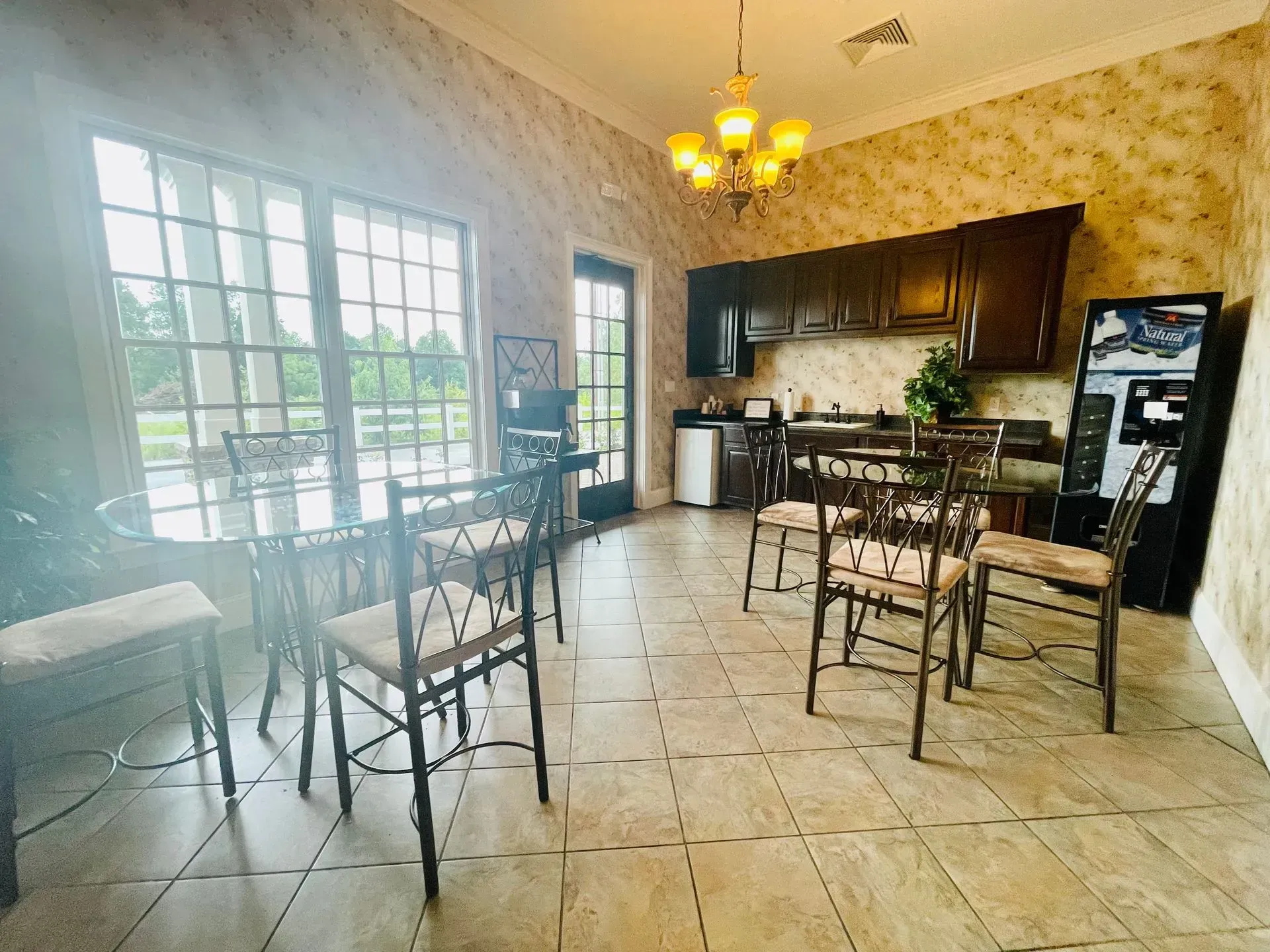 Bright kitchen and dining area with tile floor, bar stools, wood cabinets, and a chandelier