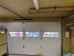 White garage door with small windows under a ceiling-mounted opener in a beige garage