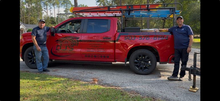 Red pickup truck with rooftop ladder rack parked outdoors, with two people standing beside it.