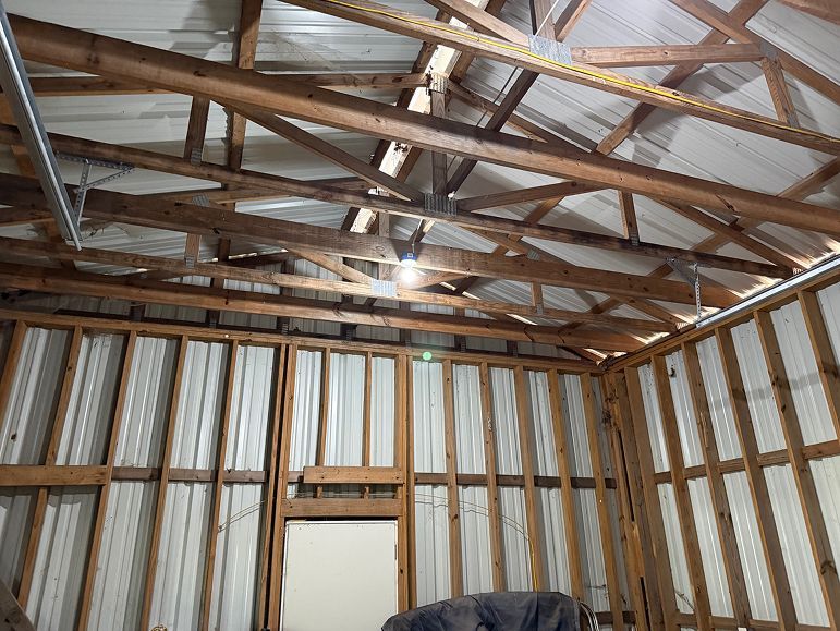 Interior of a small unfinished shed with corrugated metal walls and exposed wooden roof trusses