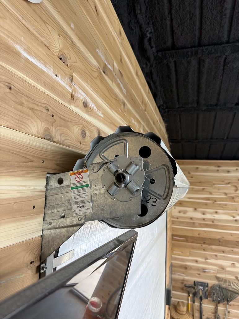 Close-up of a metal lathe chuck and tool holder against a wood-paneled workshop wall.