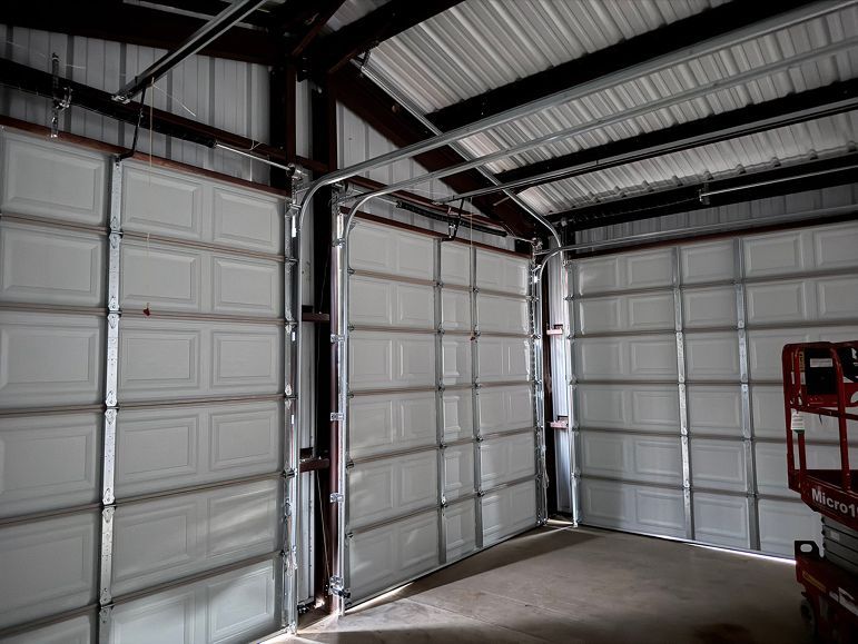 Empty metal garage interior with closed sectional doors and a concrete floor
