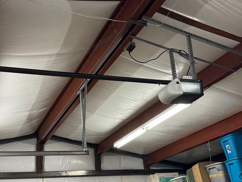 Ceiling-mounted garage door opener on exposed beams in a warehouse or garage interior
