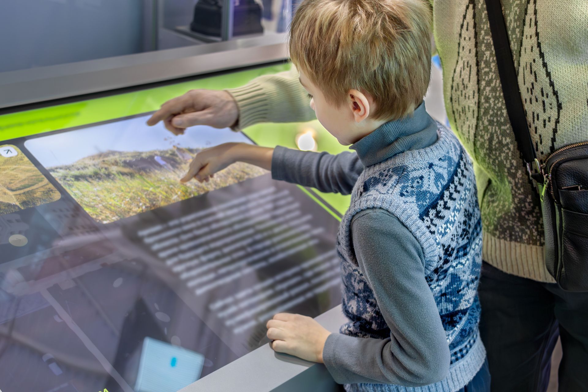 A young boy is playing a game on a touch screen.