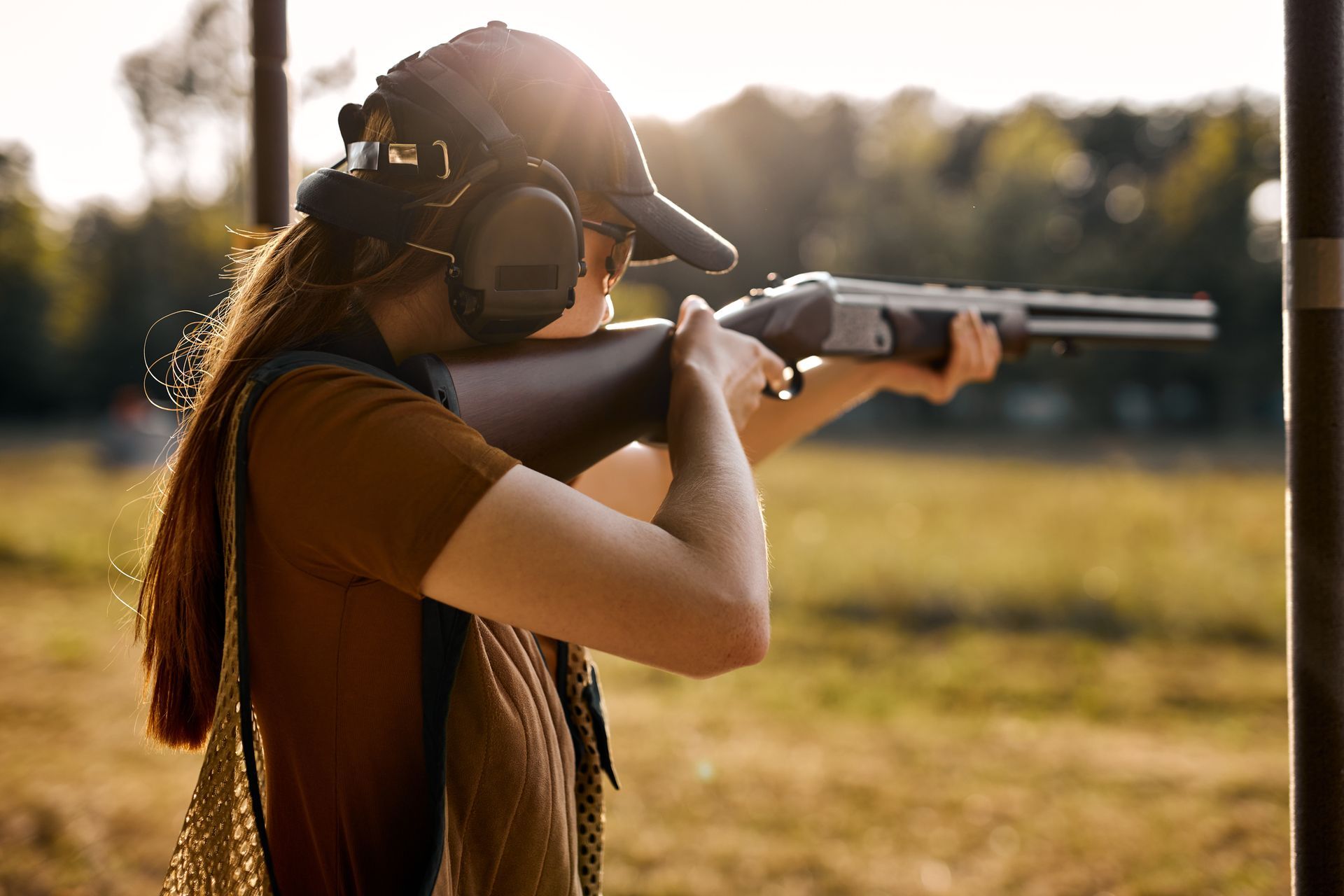 A women holding a shotgun in the outdoors.
