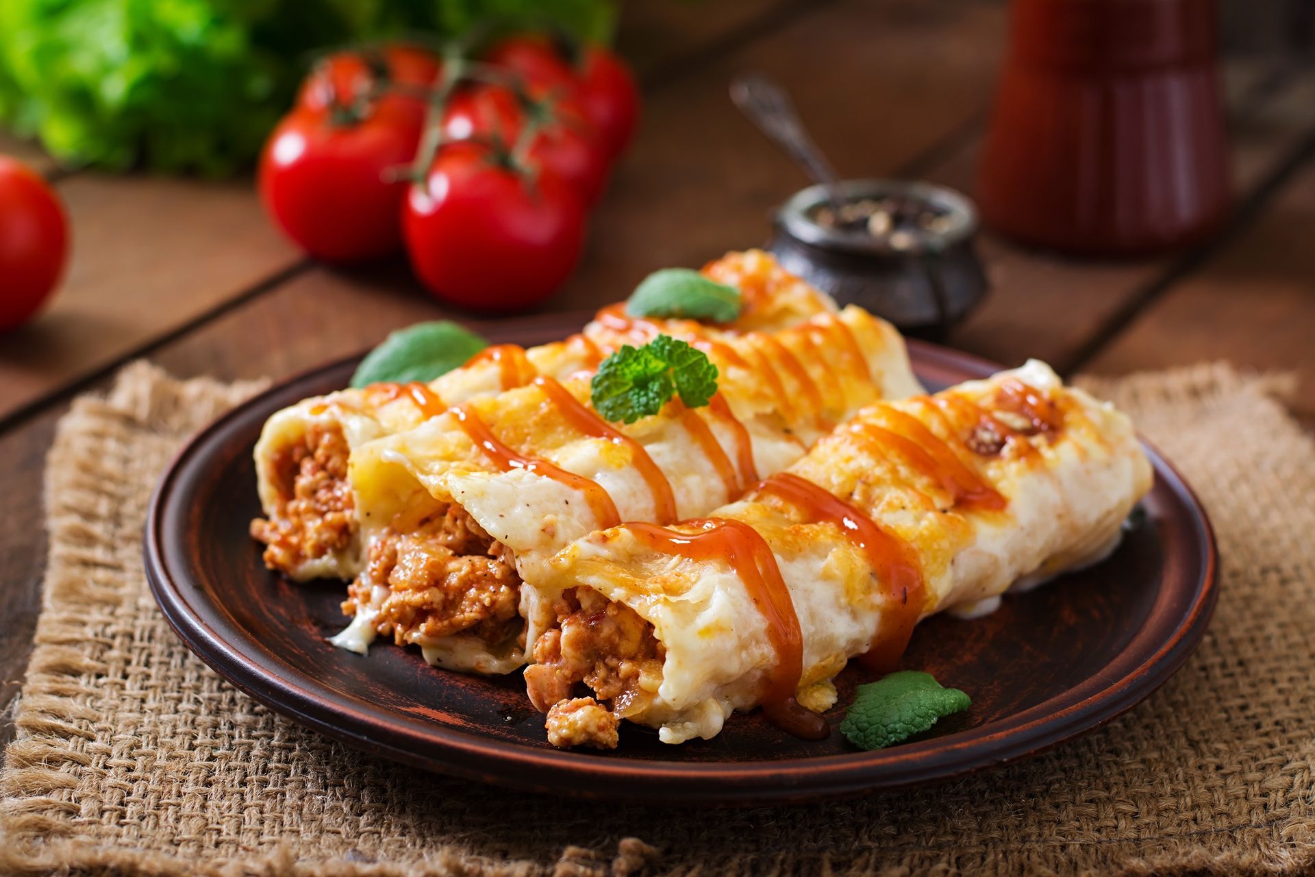 Two enchiladas with meat and cheese on a plate on a wooden table.