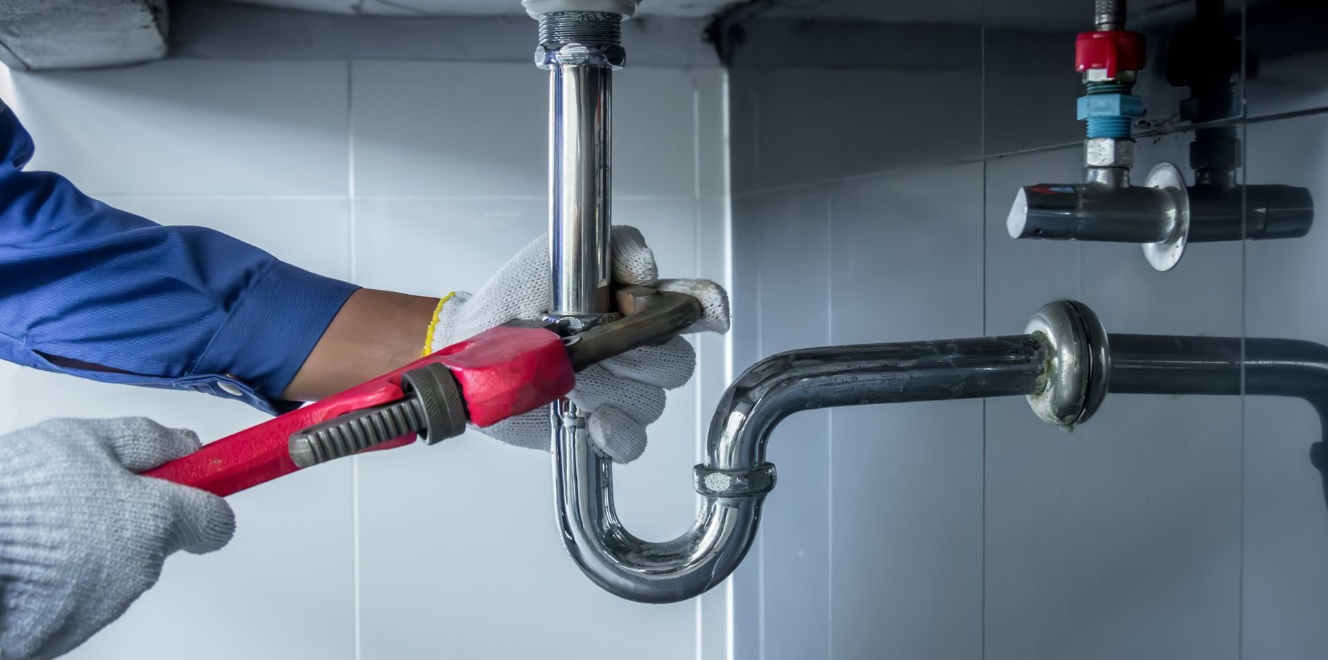 View of hands of a plumber fixing a sink with a wrench. View of hands of a plumber fixing a sink with a wrench.