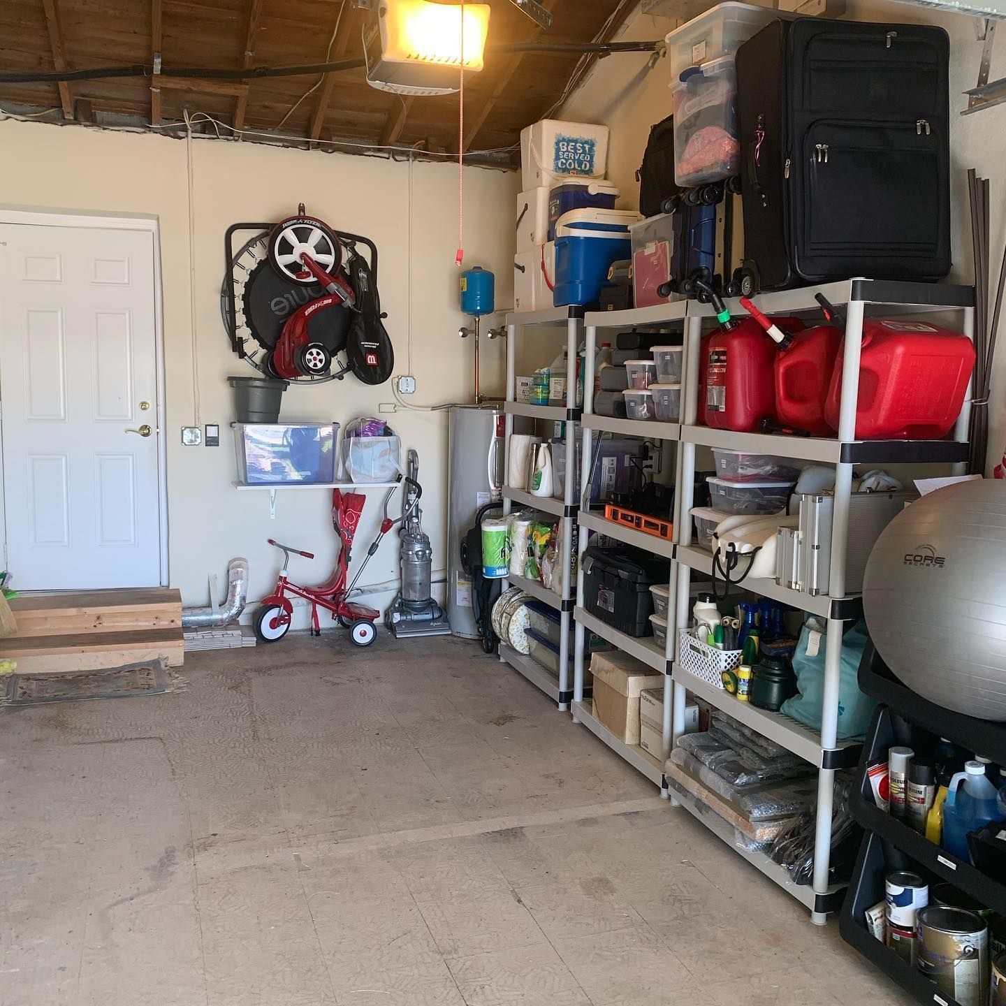 Cluttered garage interior: shelves, storage, door on left, scooter.