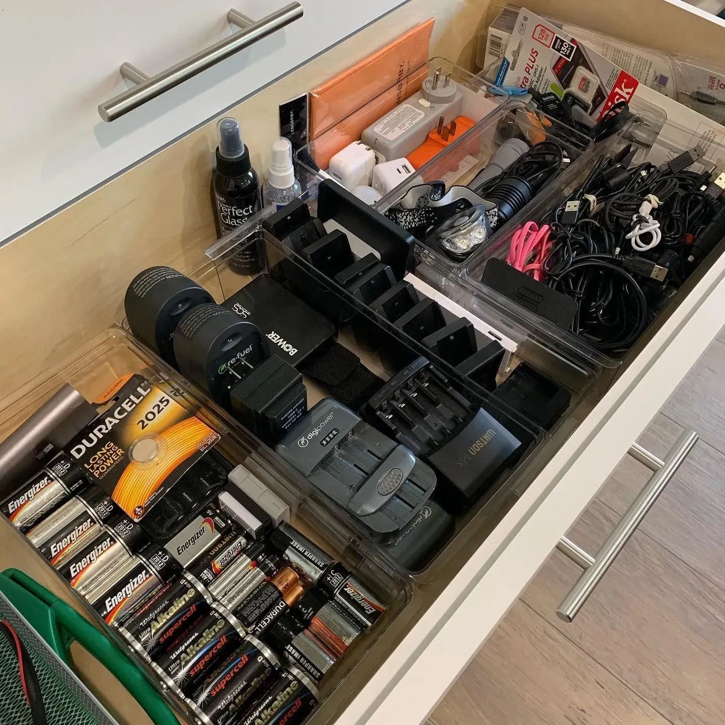 A drawer filled with a variety of items including duracell batteries