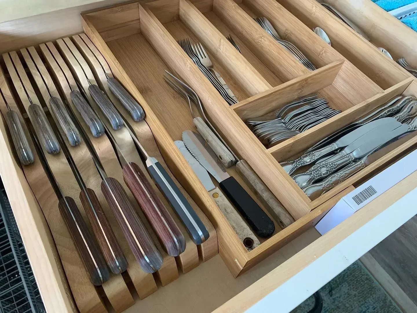 A wooden drawer filled with knives and forks