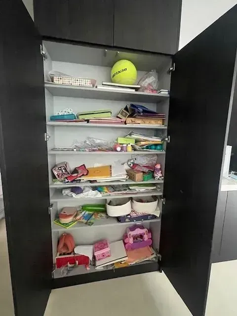 A room with a changing table and shelves filled with toys.