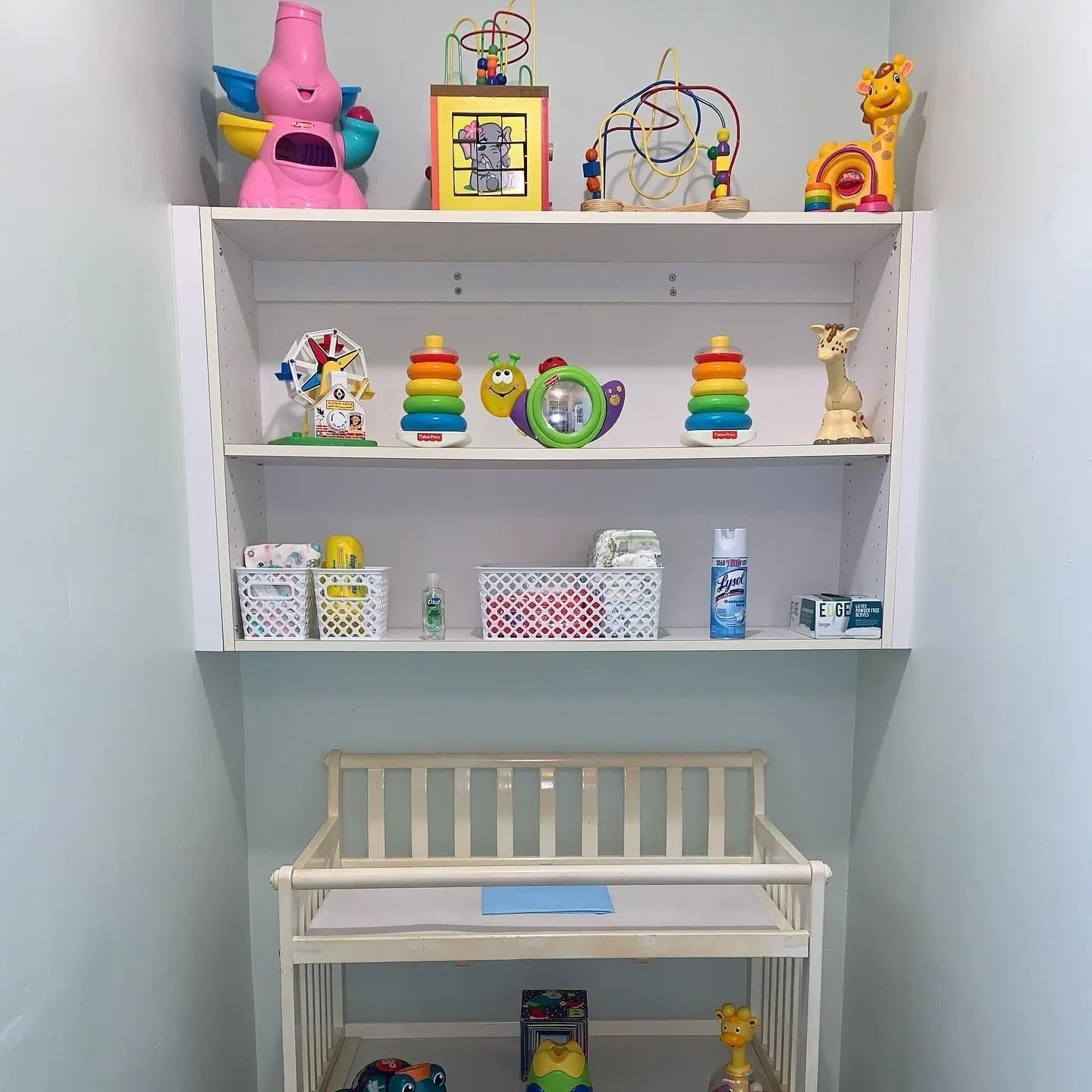 A room with a changing table and shelves full of toys