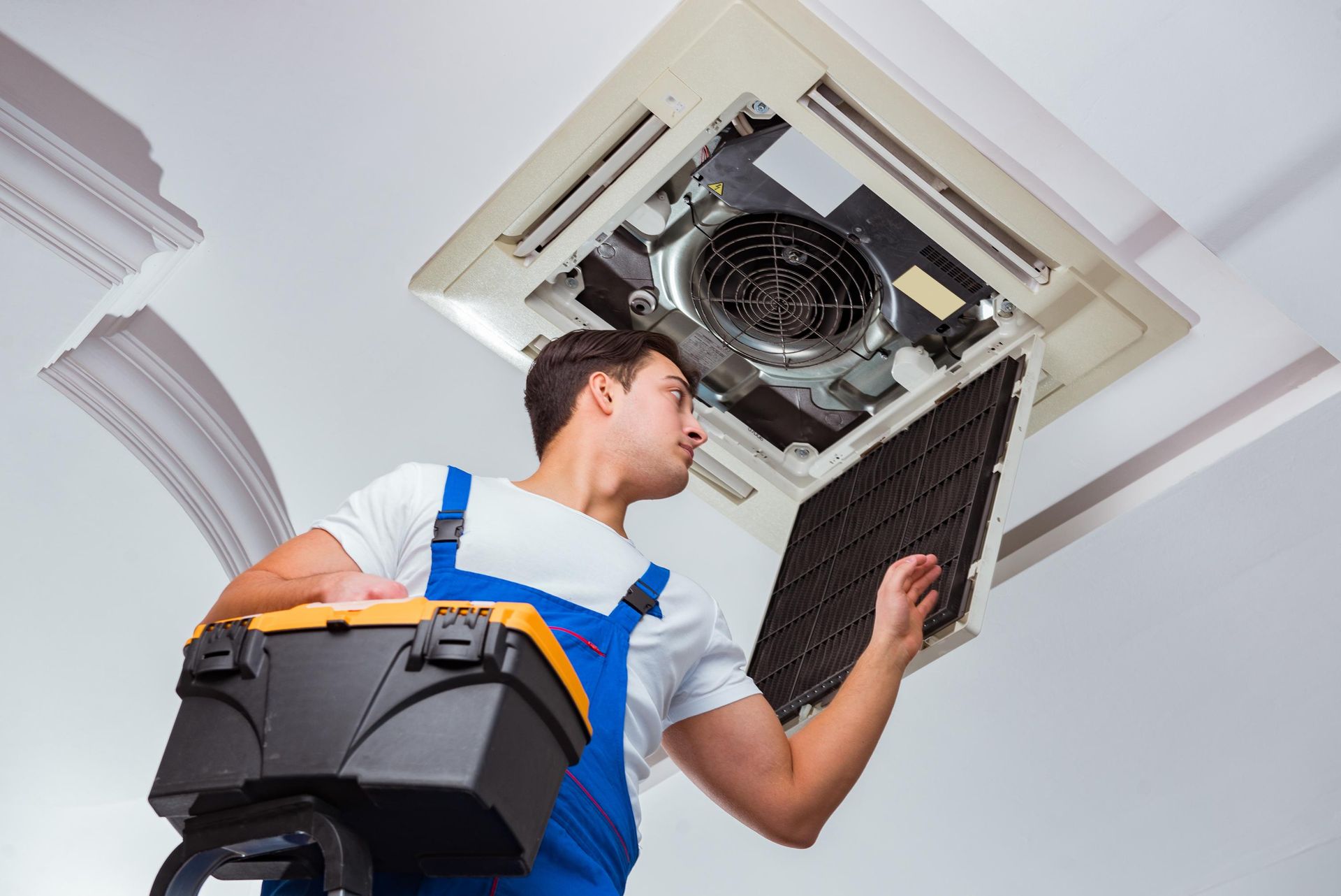 a man is cleaning a ceiling fan with a vacuum cleaner .