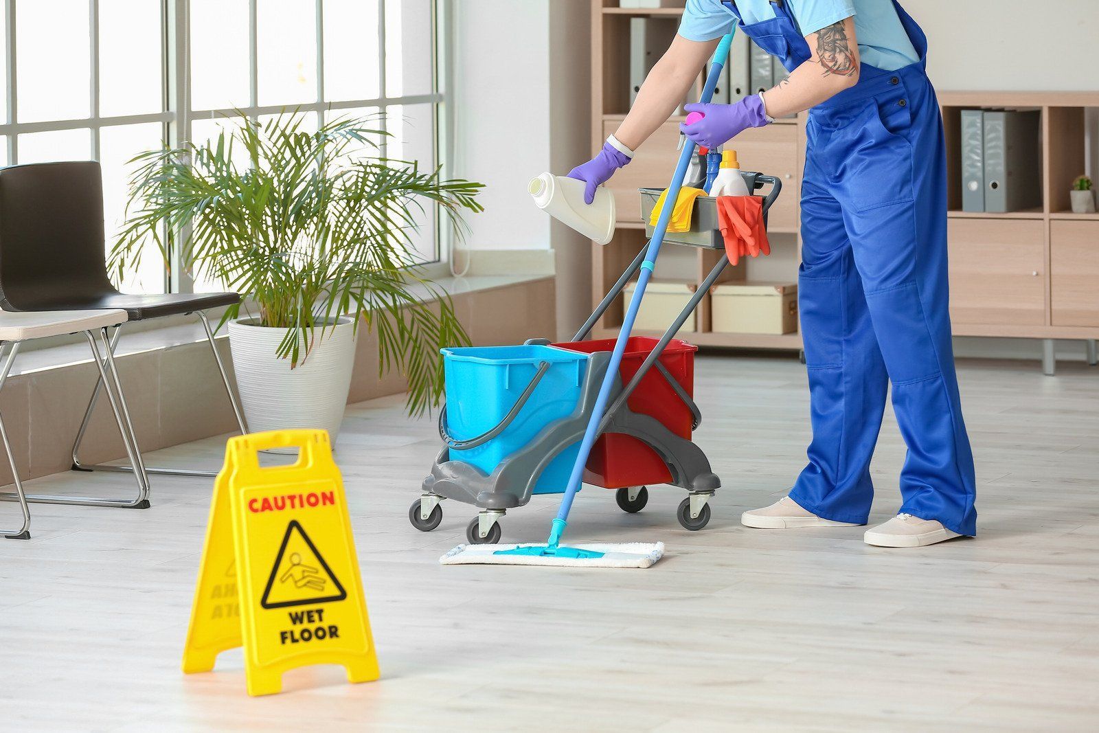 Person mopping a wet floor in an office. A yellow