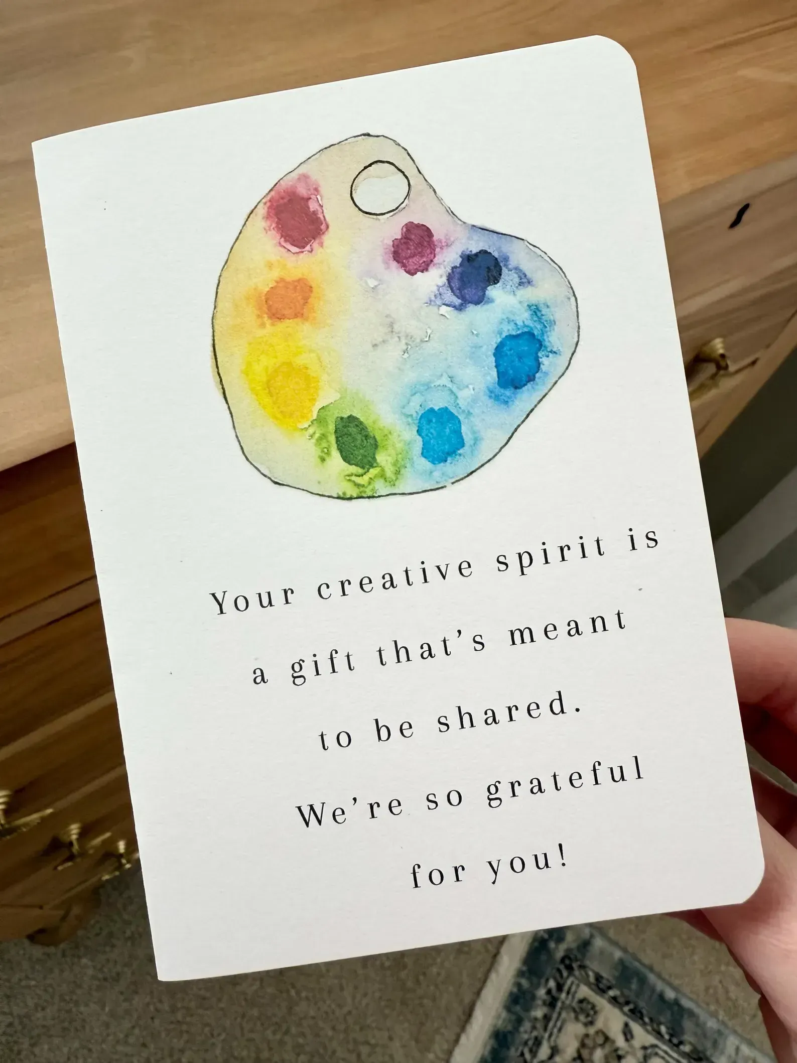 Paint palette drawing with rainbow paint spots on a white card with small text below.