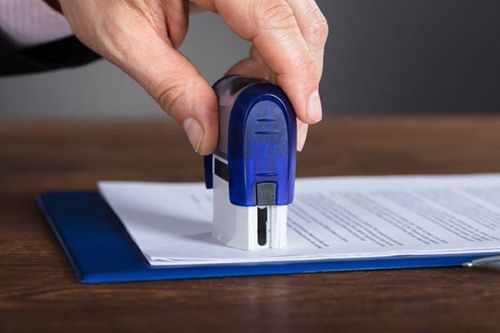 A person is putting a stamp on a piece of paper.