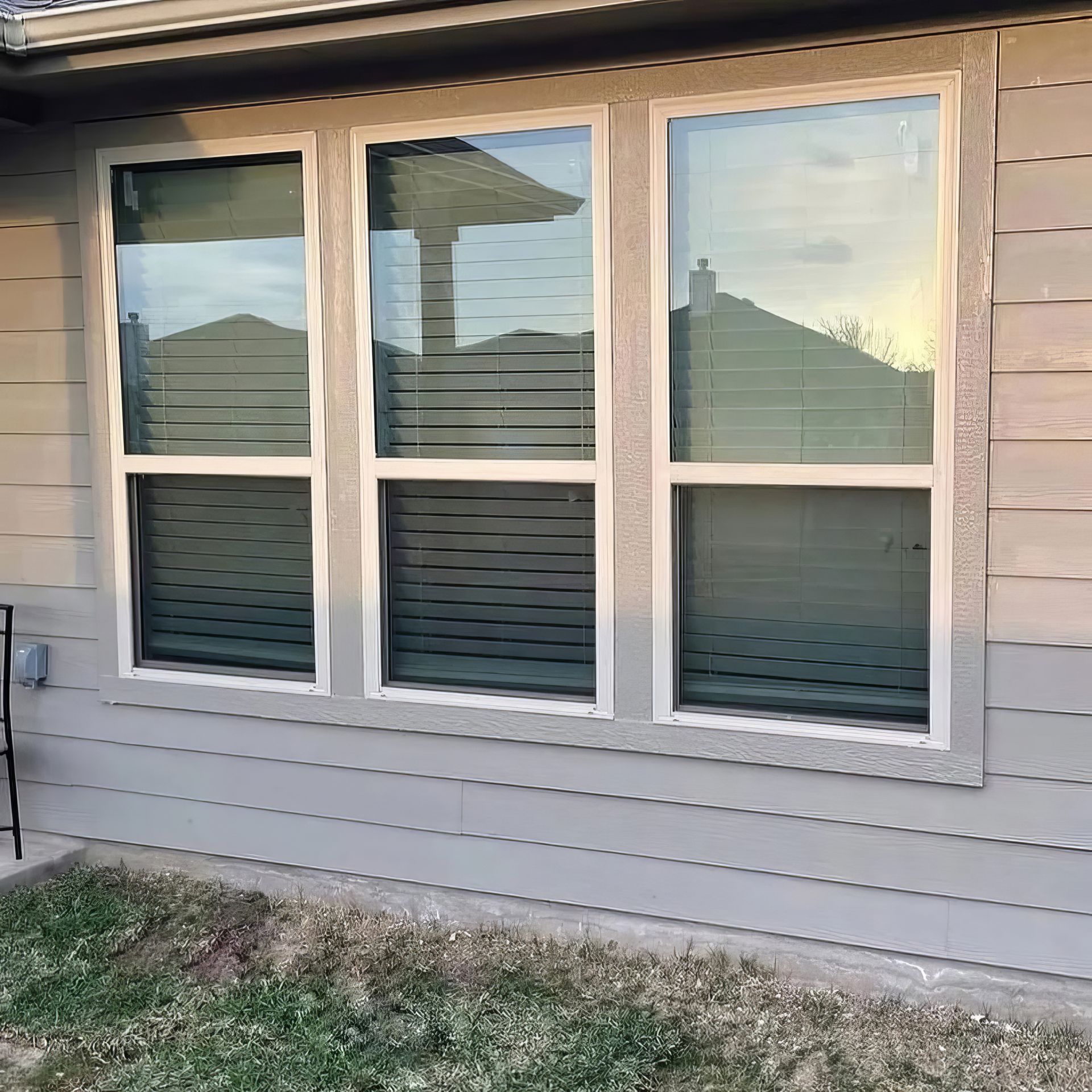 House exterior with three-pane windows and beige siding reflecting the sky