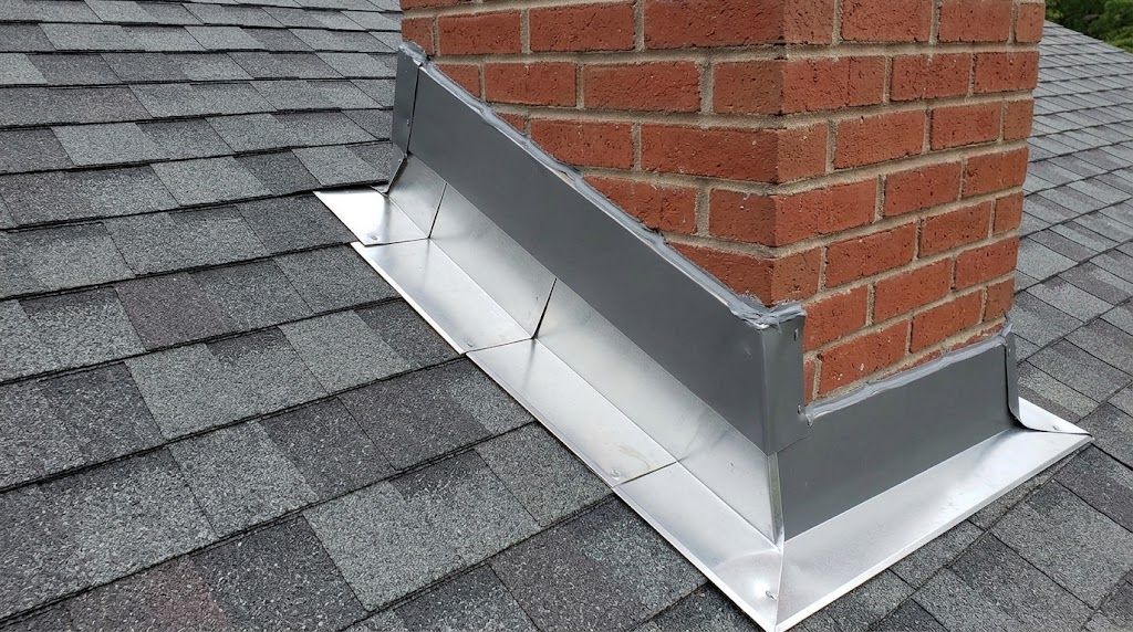 Red metal roof vent flashing around a brick chimney on a shingled roof