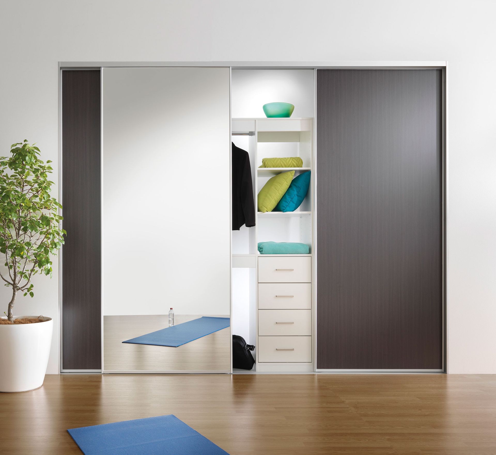 Mirror and woodgrain sliding wardrobe doors with yoga mat on timber floor and pot plant
