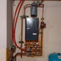 Copper pipes and heating system components mounted on a wooden board.