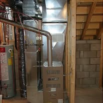 Furnace and ductwork inside a concrete block wall, pipes and other equipment visible.
