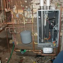 Copper pipes and a boiler system installed on a wall with other equipment.
