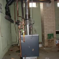 Furnace with pipes and chimney in a basement.