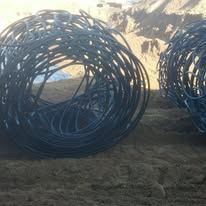 Two large coiled black pipes on brown ground.