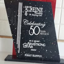 Black and white commemorative plaque celebrating 50 years of Peine Plumbing. Includes Armstrong Air logo.