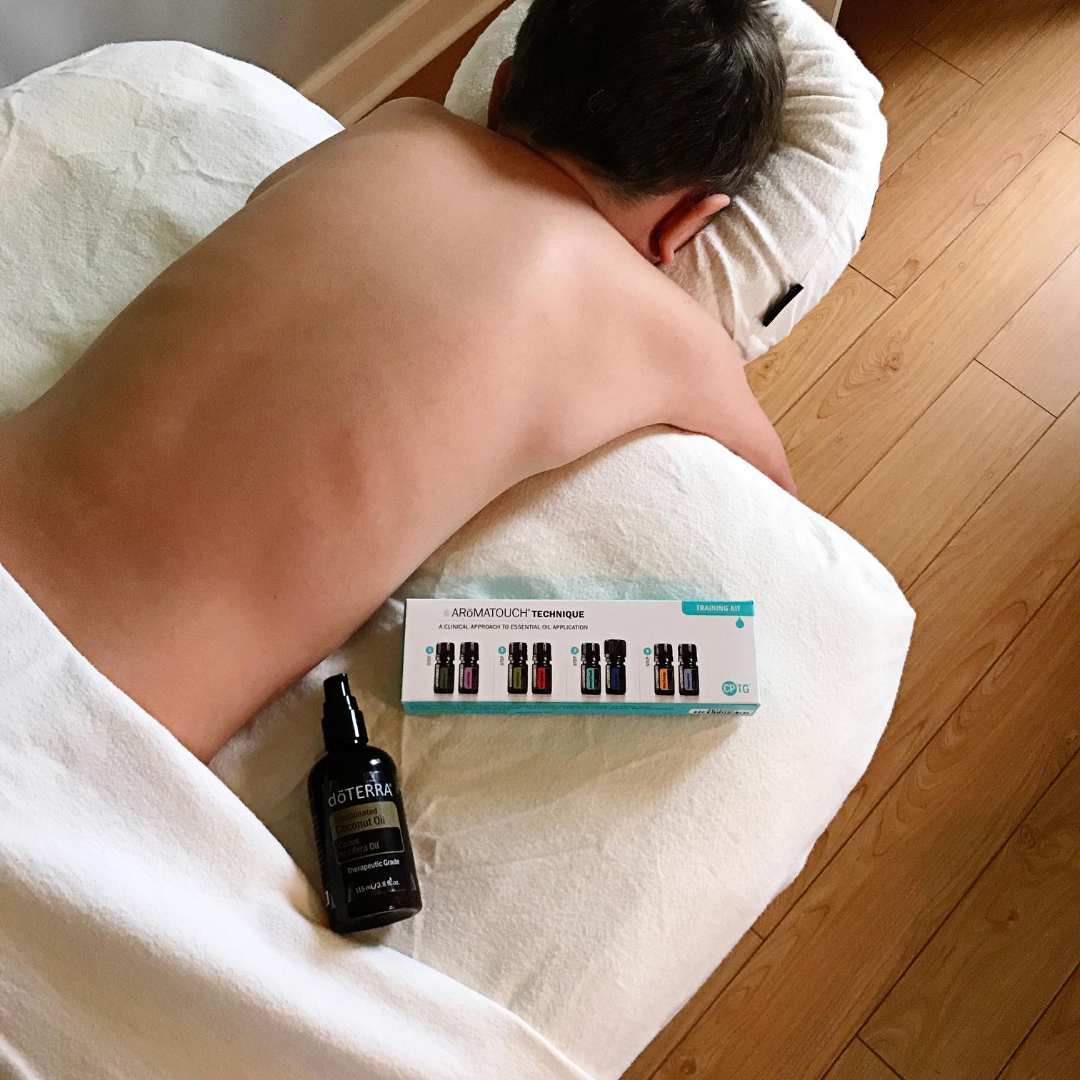 Een persoon ligt op zijn buik op een massagetafel met essentiële oliën.
