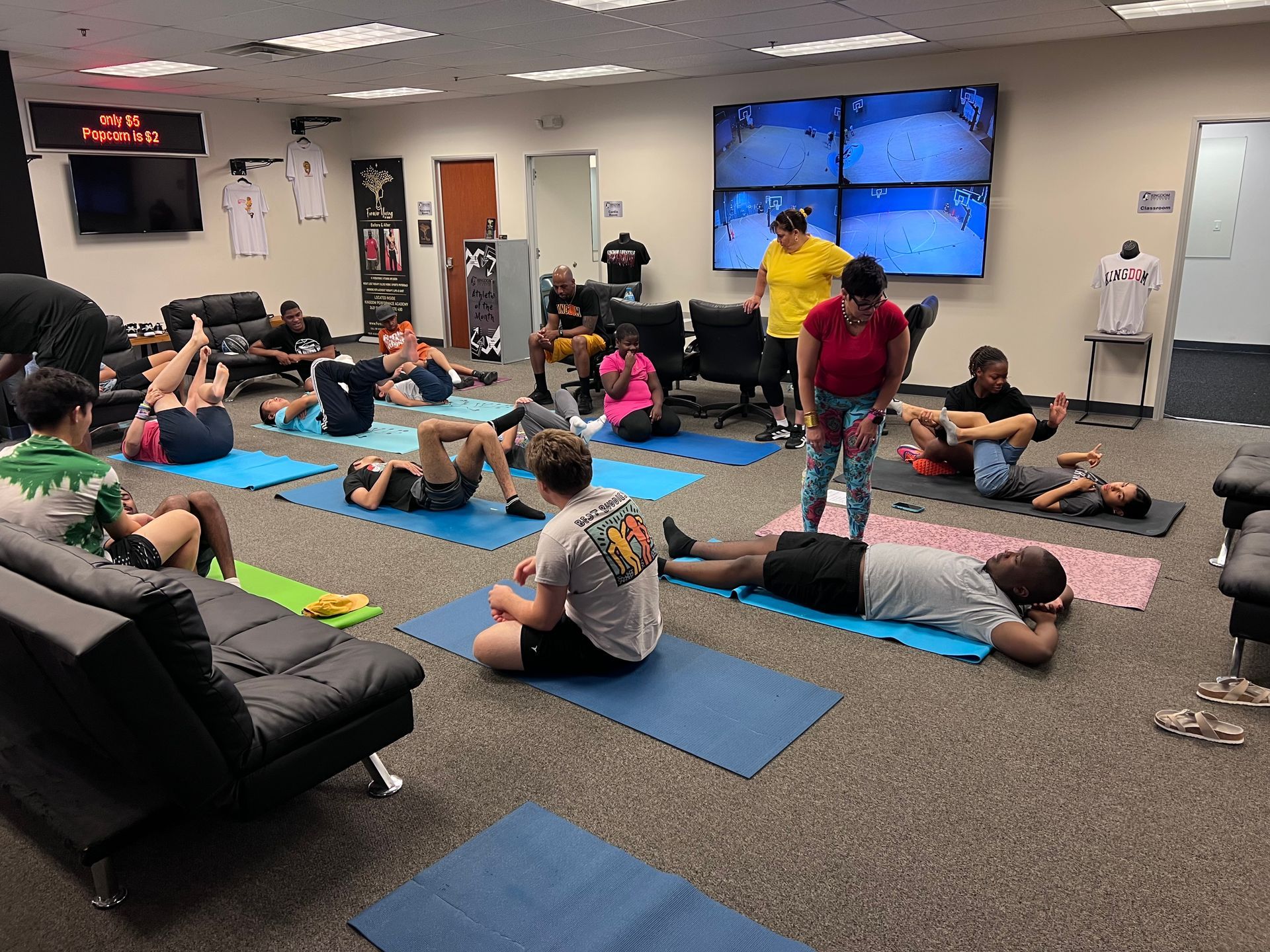 A group of people doing yoga on mats indoors. A man is leading the class.
