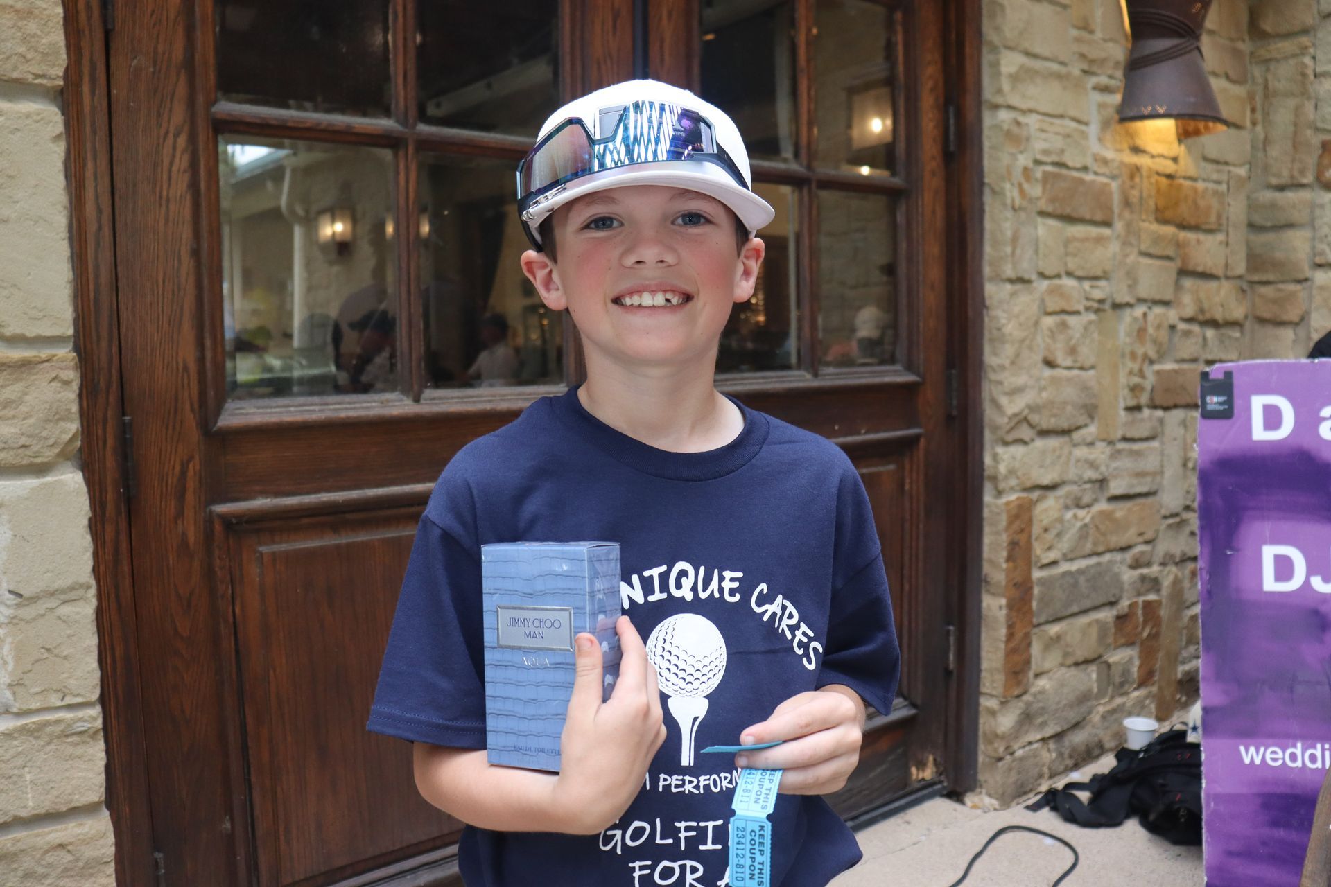 Young boy in a cap and sunglasses holding a gift, smiling, with a