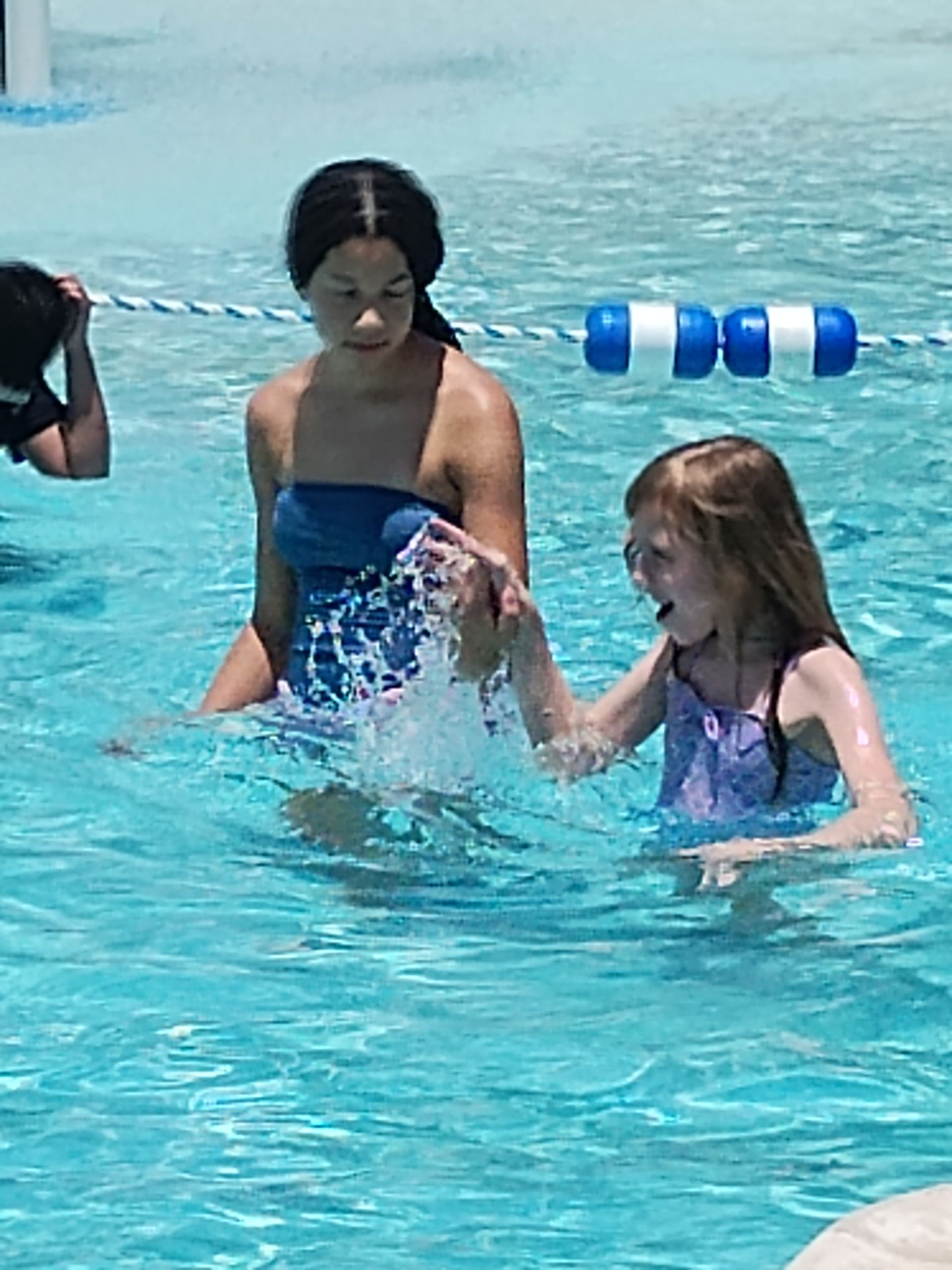 Woman and child playing in a swimming pool. Woman splashes water on the child.