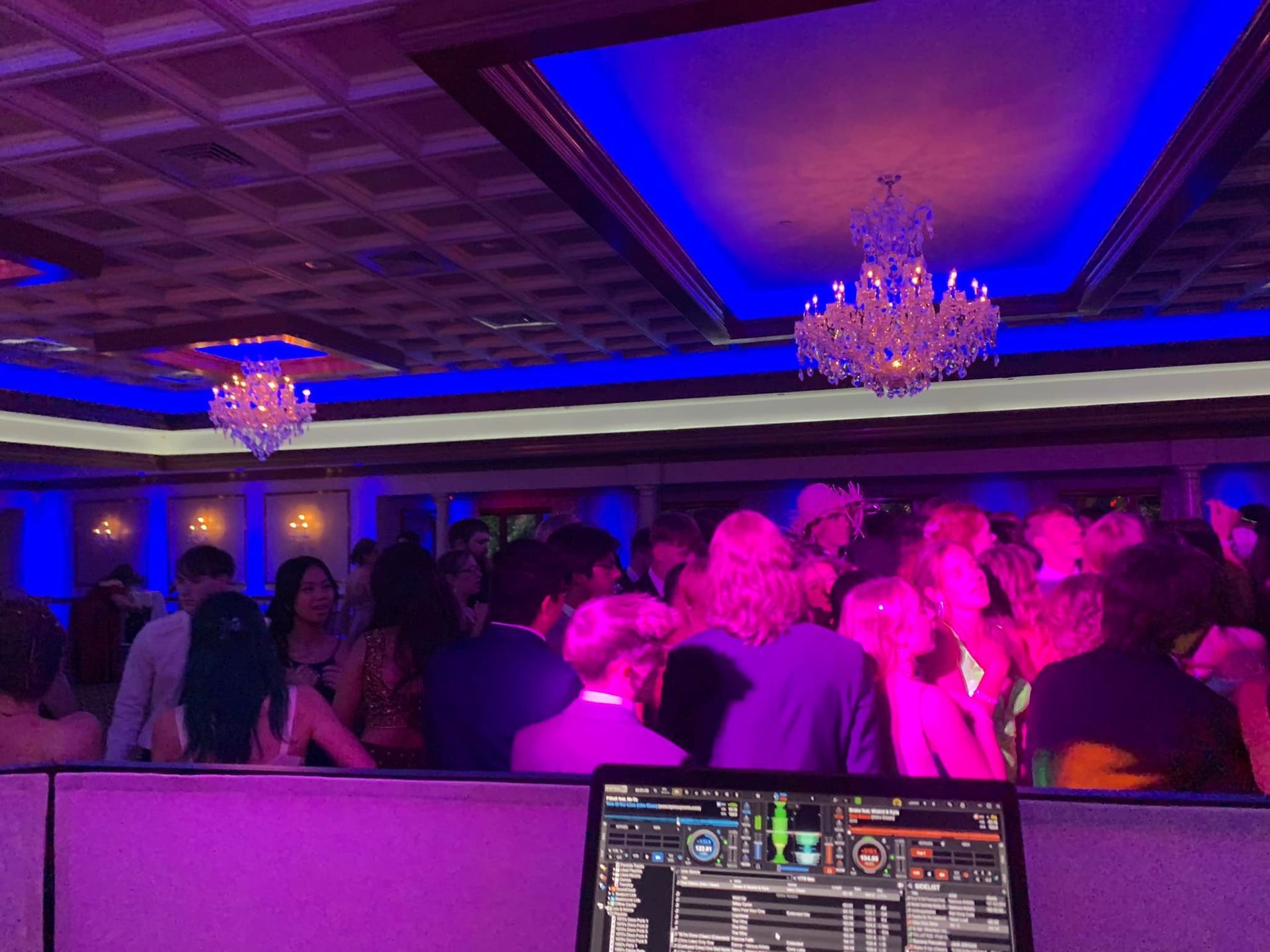 A group of people are dancing in a room with purple lights.