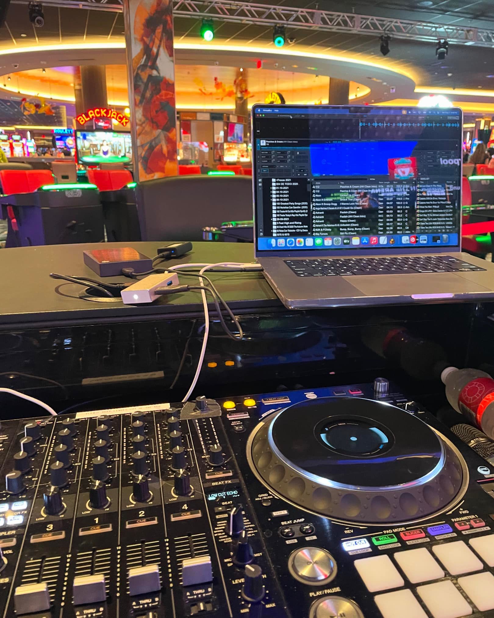 A laptop is sitting on a table next to a dj controller.