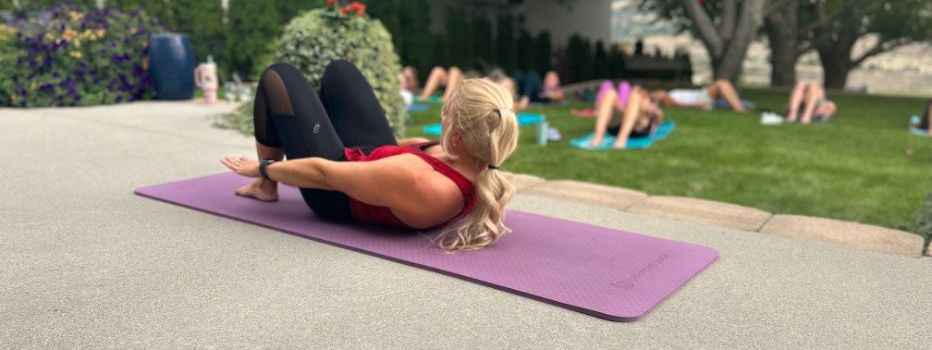 a woman is laying on a purple yoga mat outside .