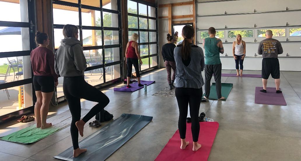 a group of people are standing on yoga mats in a room .