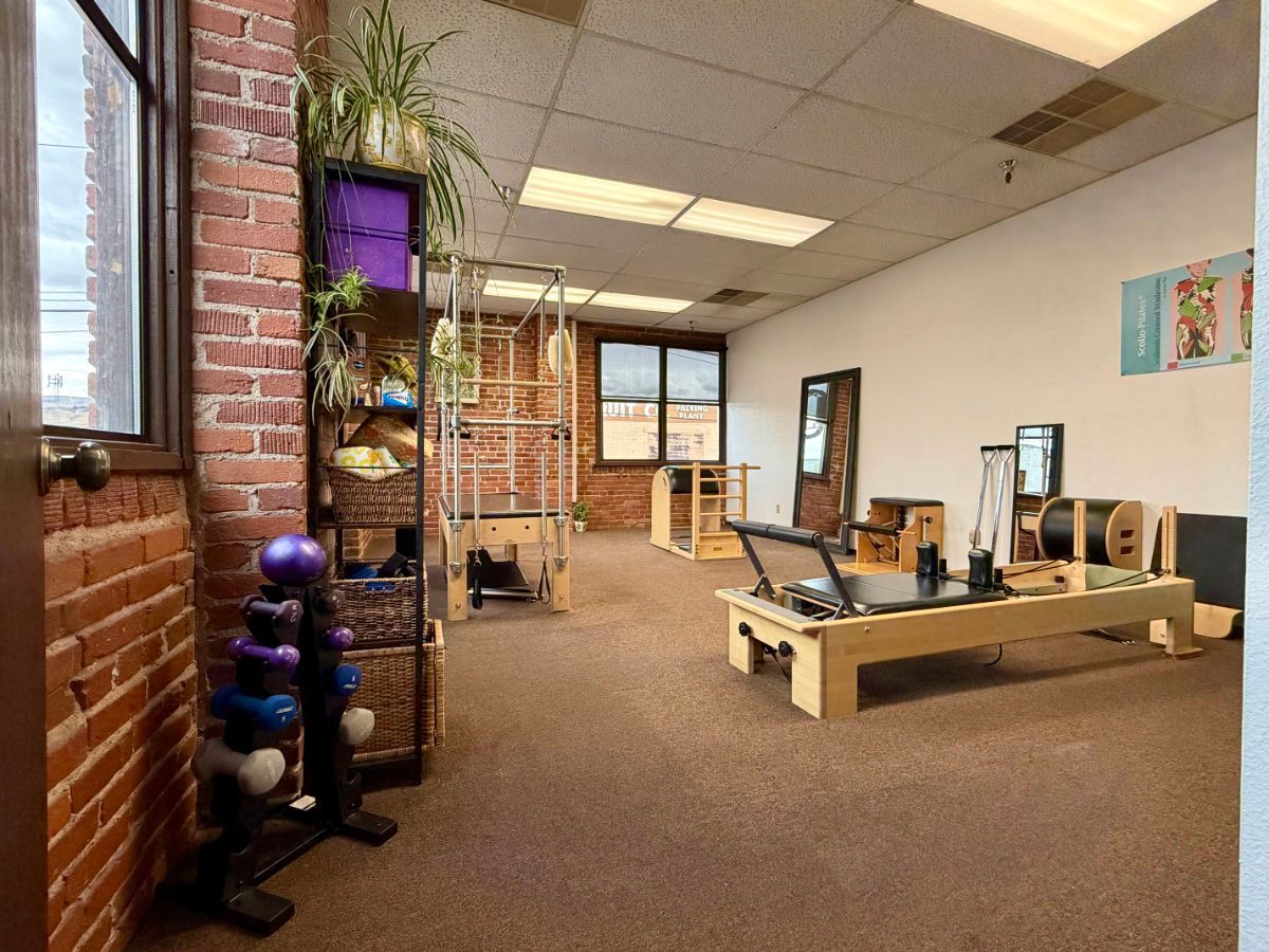Open office gym area with workout equipment, wooden flooring, and a brick wall.