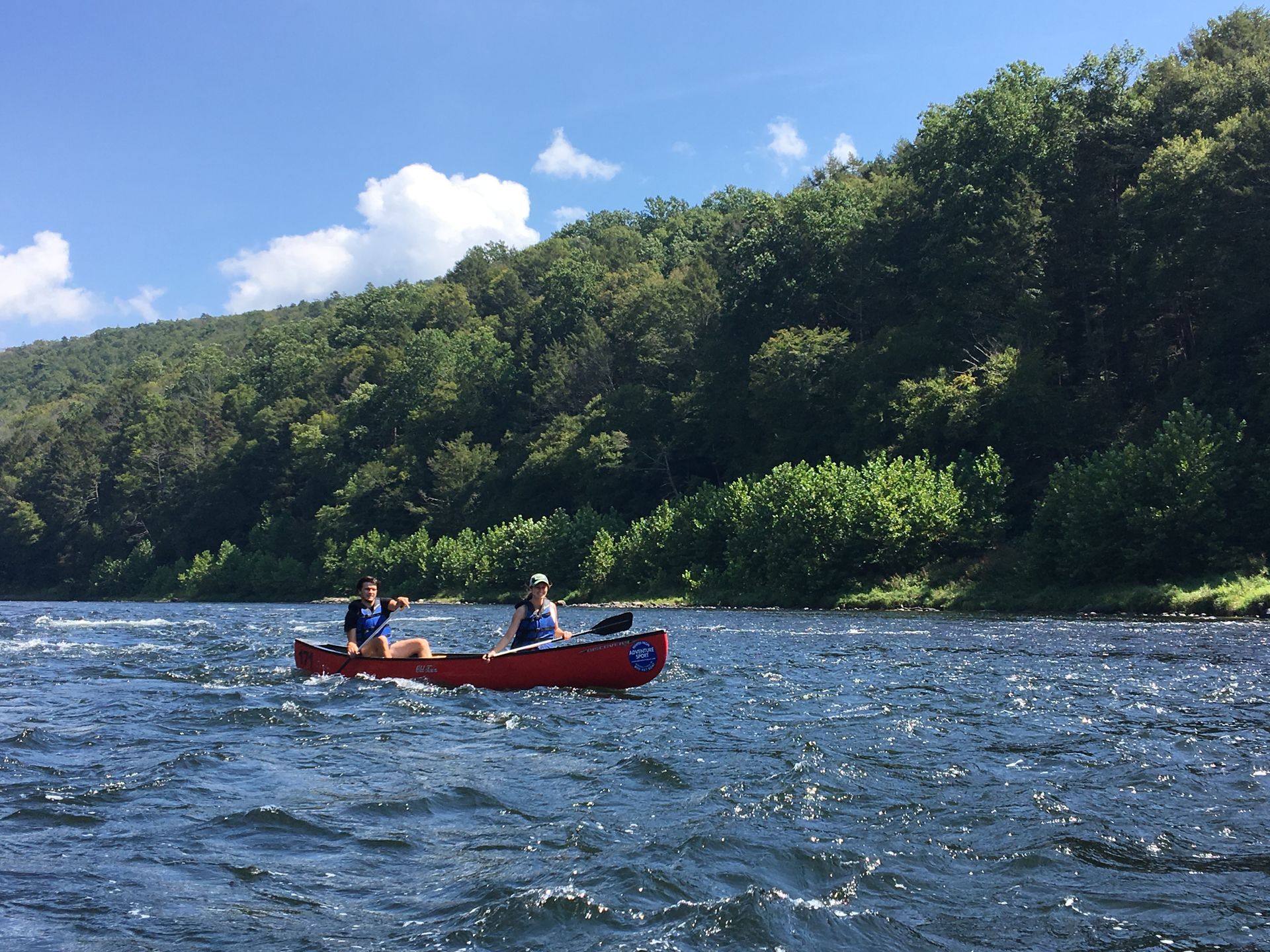 Two people in a red adventure sports canoe on a river