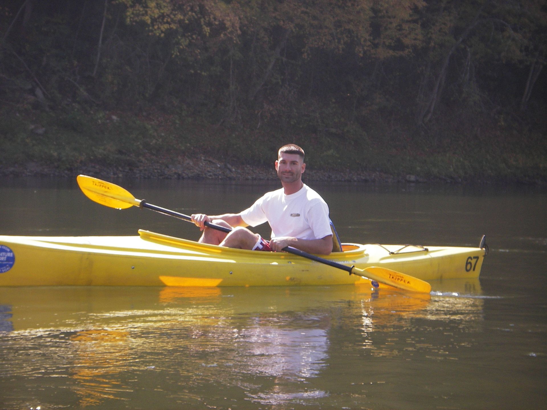 A man in a yellow adventure sports kayak with the number 67 on it