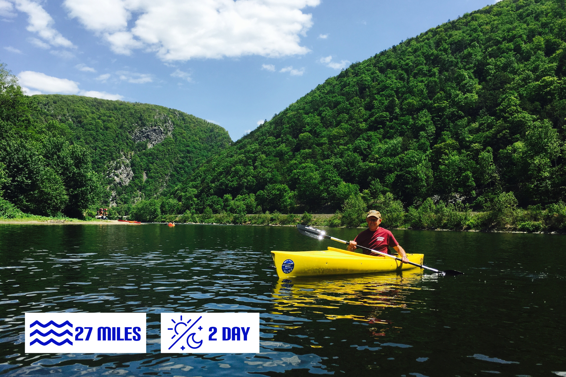 A man from adventure sports in a yellow kayak on a lake with mountains in the background