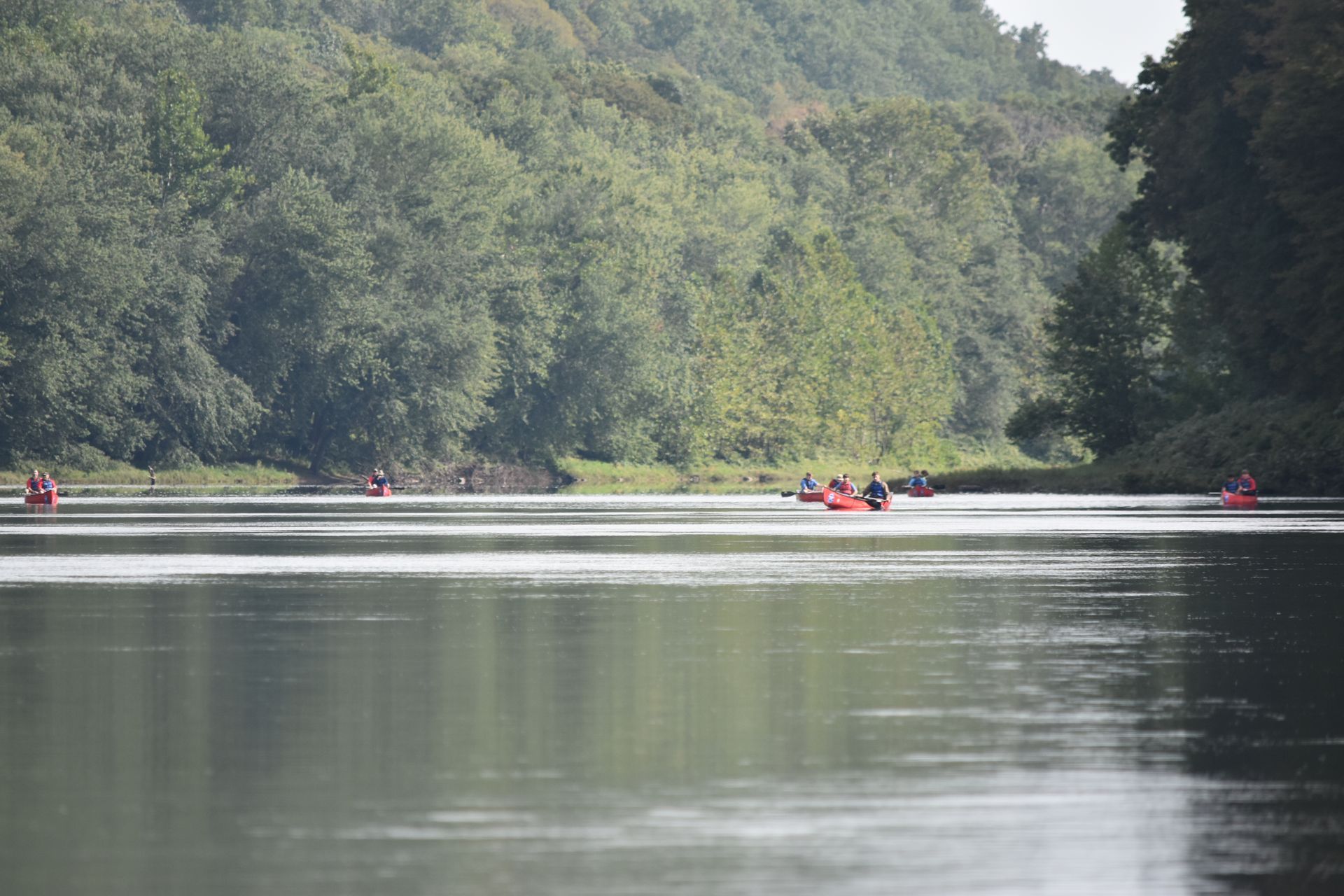 A group of people are rowing adventure sports kayaks down a river.