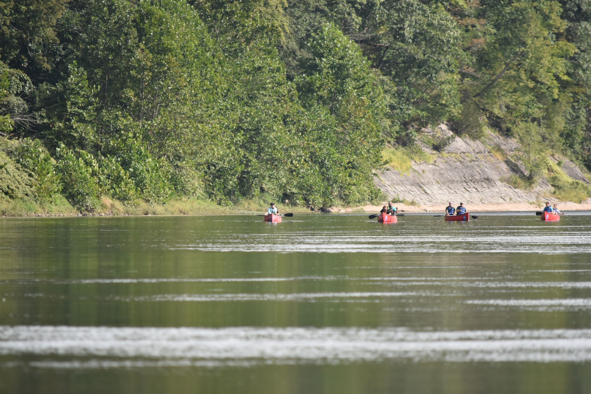 A group of people are rowing adventure sports kayaks on a lake.